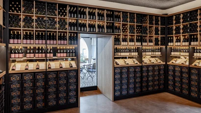 Weinkeller mit Regalen voller Weinflaschen und einem Ausgang zu einer Terrasse