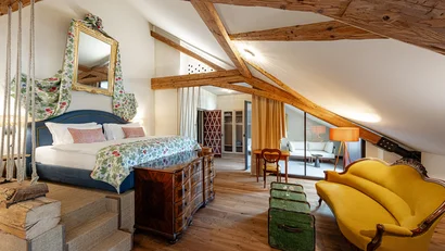 Gemütliches Schlafzimmer mit Holzbalken, gelbem Sofa und antiken Möbeln