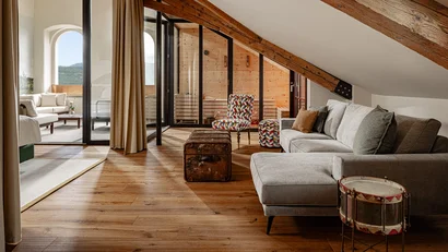 Gemütliches Wohnzimmer mit Holzboden, einer Couch und Zugang zur Sauna und Terrasse