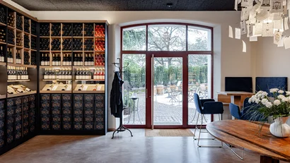 Weinlager mit Flaschenregal und Sitzbereich neben großen Fenstern