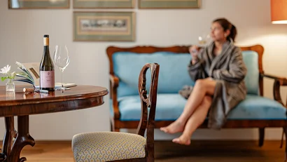 Frau entspannt mit Wein in einem gemütlichen Wohnzimmer mit antiken Möbeln