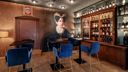 Weinbar mit blauen Stühlen, Holzmöbeln und historischem Frauenporträt an der Wand