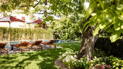 Garten mit Liegestühlen und Sonnenschirmen neben einem Pool