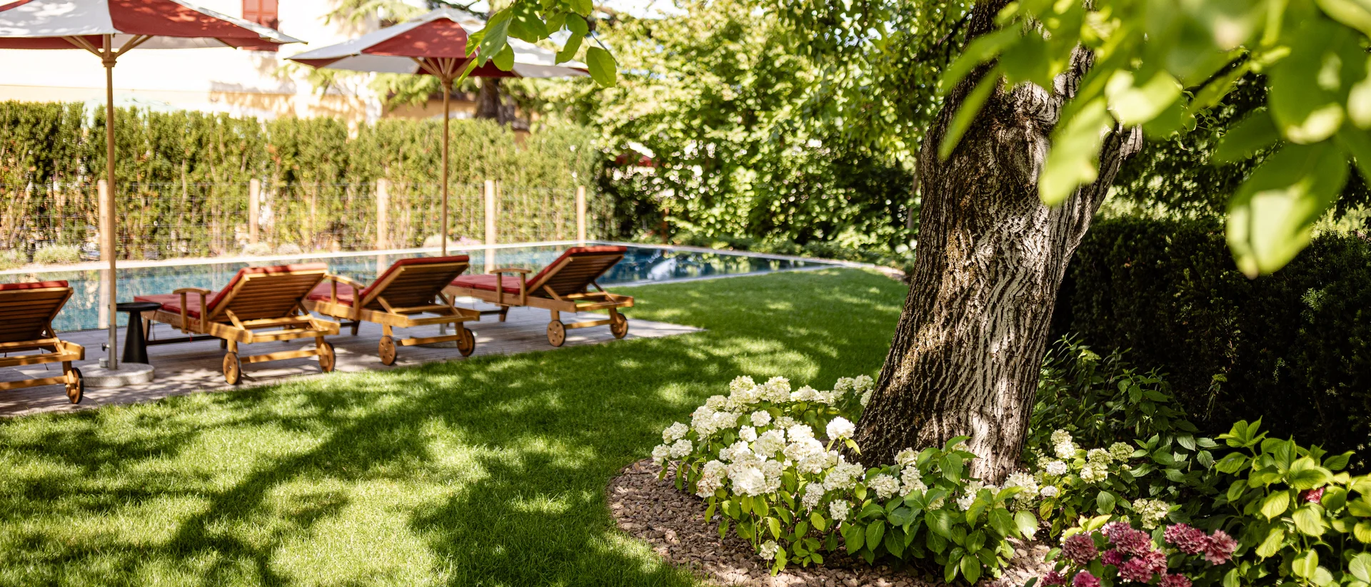 Garten mit Liegestühlen und Sonnenschirmen neben einem Pool