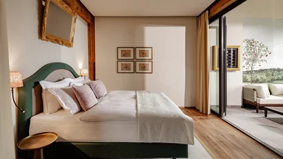 Modernes Schlafzimmer mit Boxspringbett und Blick auf Terrasse mit Sitzbereich