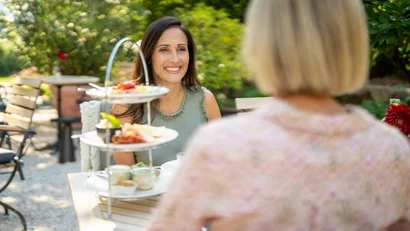 Zwei Frauen genießen Kaffee und Gebäck bei Outdoor-Café im Garten