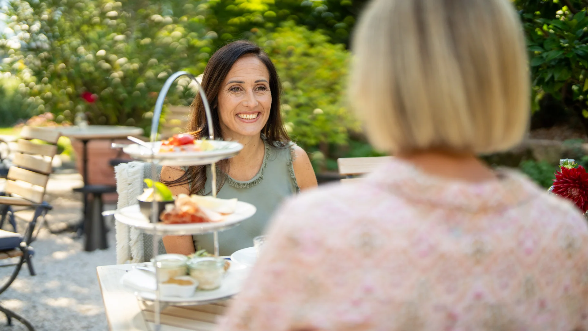 Zwei Frauen genießen Kaffee und Gebäck bei Outdoor-Café im Garten
