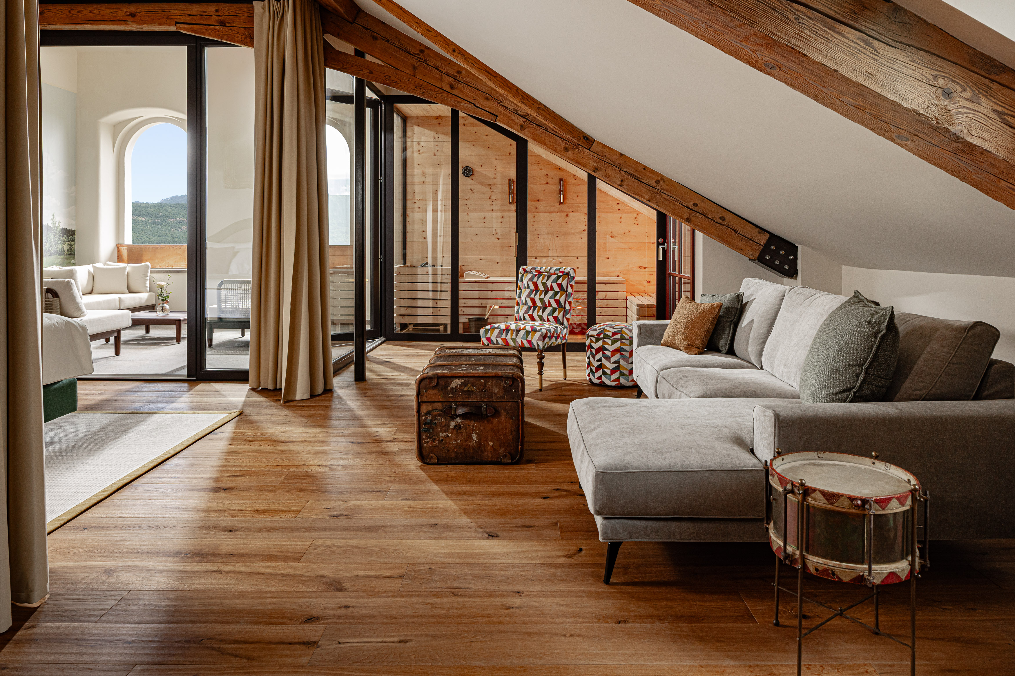 Gemütliches Wohnzimmer mit Holzboden, einer Couch und Zugang zur Sauna und Terrasse